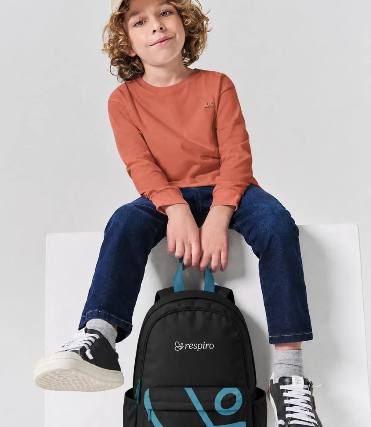 Criança sentada com uma mochila da Respiro.